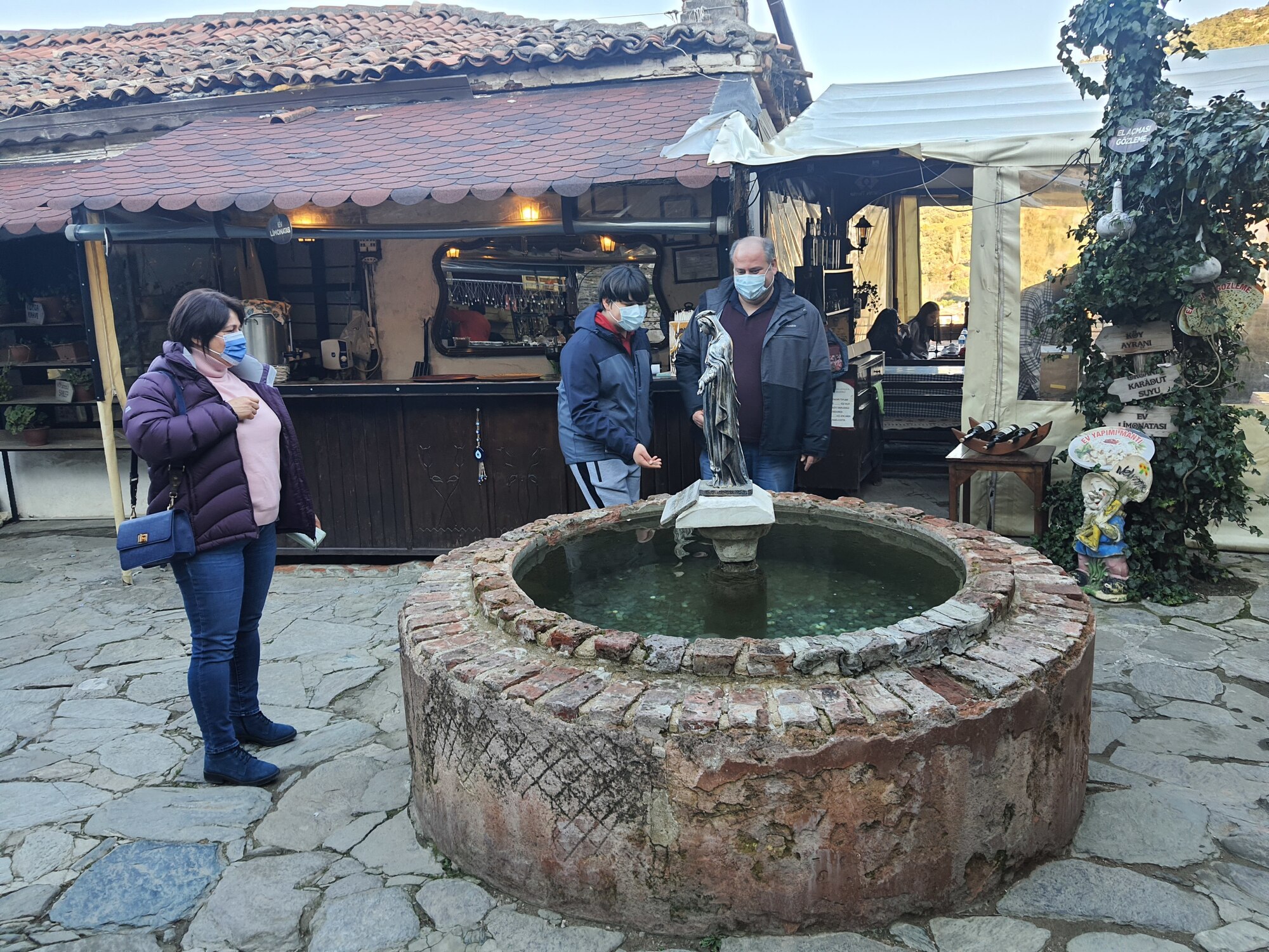 Locals try to get their coin to fall into a hole inside a well in the courtyard of 
a church in Şirince Feb. 19, 2022. Tourists indulge in some of the best wines 
of western Türkiye when they visit Şirince, have lunch at one of the bed-and-breakfast 
type eateries, stop by the Christian church where St. John gave sermons and 
make a wish at the well. (U.S. Air Force photo by Tanju Varlıklı