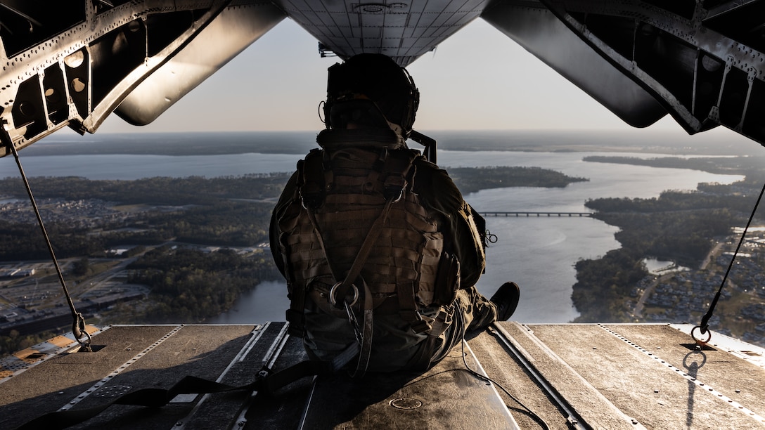 U.S. Marine Corps Staff Sgt. Ryan Beattie, crew chief with Marine Heavy Helicopter Squadron-772, 4th Marine Aircraft Wing, Marine Forces Reserve, observes terrain during a CH-53E Super Stallion helicopter flight in support of exercise Rolling Thunder on Marine Corps Air Station New River, Jacksonville, N.C., March 28, 2022. Exercise Rolling Thunder is a live-fire artillery exercise where 10th Marines, 2d Marine Division employ distributed fires via simulated Expeditionary Advanced Bases of Operation.