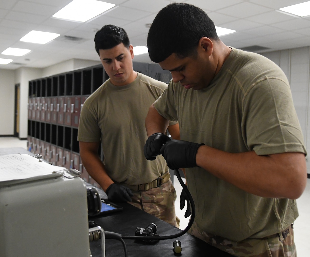 Technical Sgt. Stephen Diaz and Staff Sgt. Emanuelle Negron, 920th Operations Support Squadron aircrew flight equipment craftsmen, perform helmet inspections for aircrew use at Patrick Space Force Base, Fla., April 2, 2022. AFE is a team of 27 Airmen whose main role is to maintain, test, and inspect the flight gear used by all aircrew. (U.S. Air Force photo by Staff Sgt. Darius Sostre-Miroir)
