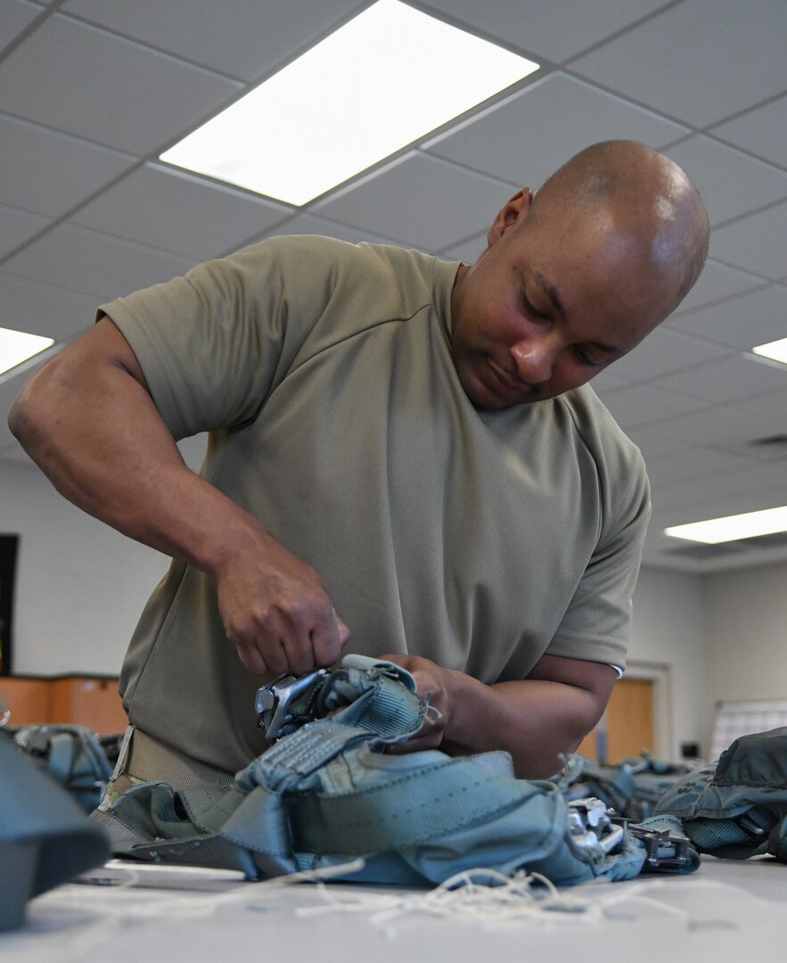 Senior Airman Brian McKithen, 920th Operations Support Squadron aircrew flight equipment craftsman, fixes frayed strings on a harness at Patrick Space Force Base, Fla., April 02, 2022. AFE is a team of 27 Airmen whose main role is to maintain, test, and inspect the flight gear used by all aircrew. (U.S. Air Force photo by Staff Sgt. Darius Sostre-Miroir)