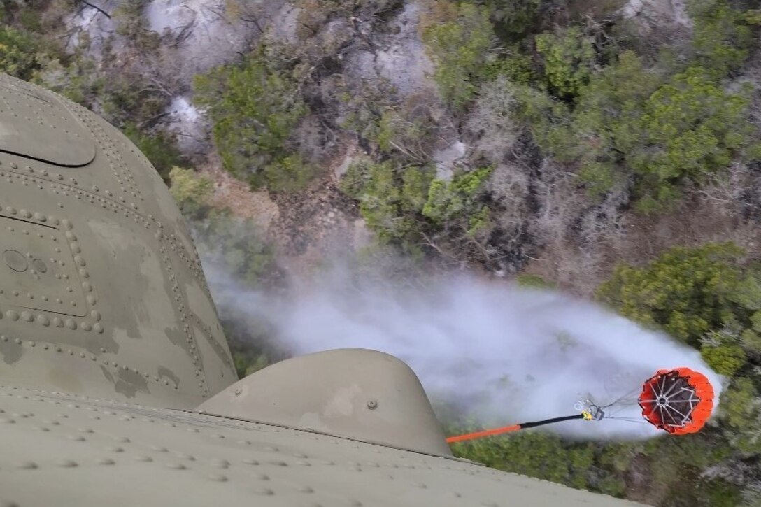 A helicopter drops water over wildfires.