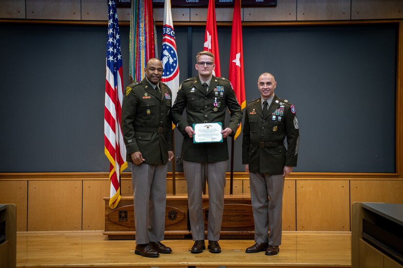 army soldiers in uniform on a stage presenting awards.