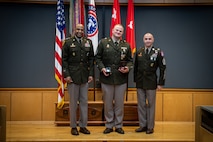 army soldiers in uniform on a stage presenting awards.