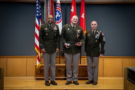 army soldiers in uniform on a stage presenting awards.