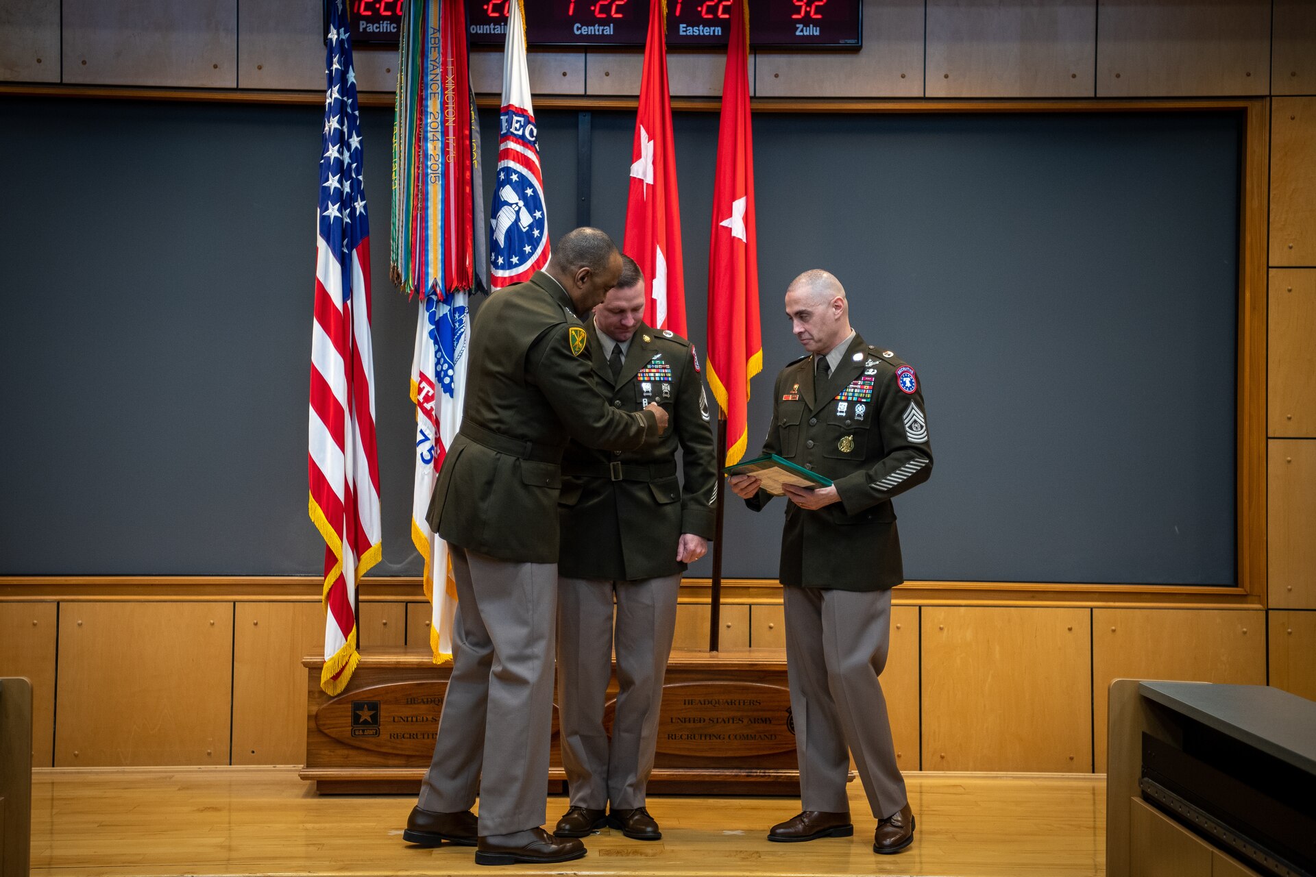 army soldiers in uniform on a stage presenting awards.