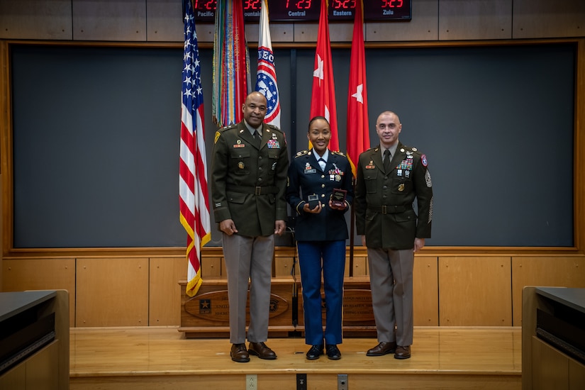 army soldiers in uniform on a stage presenting awards.