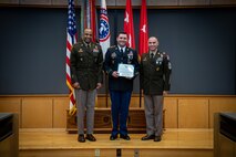 army soldiers in uniform on a stage presenting awards.