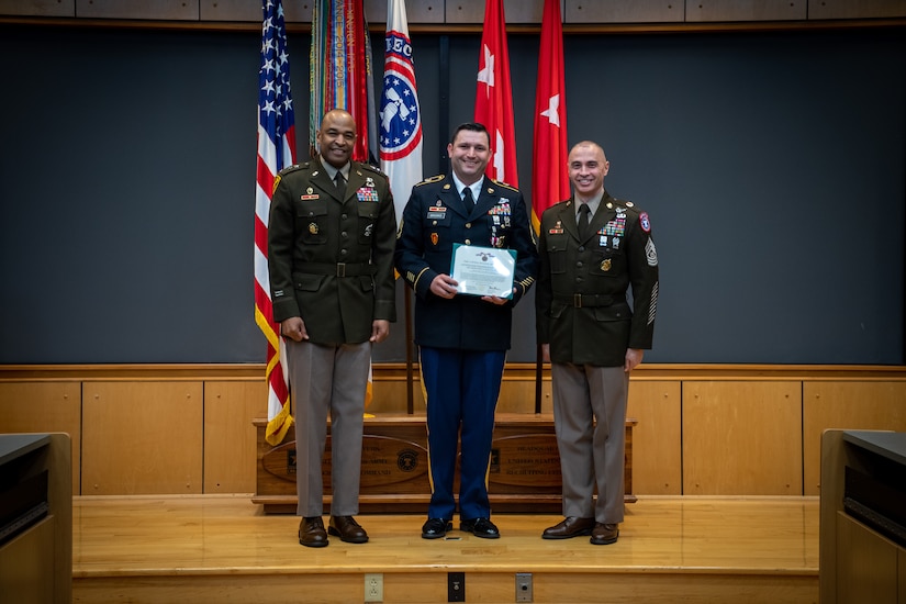 army soldiers in uniform on a stage presenting awards.