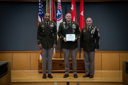 army soldiers in uniform on a stage presenting awards.