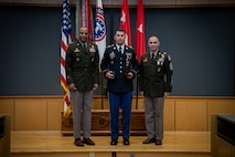 army soldiers in uniform on a stage presenting awards.