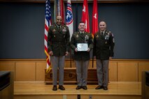 army soldiers in uniform on a stage presenting awards.