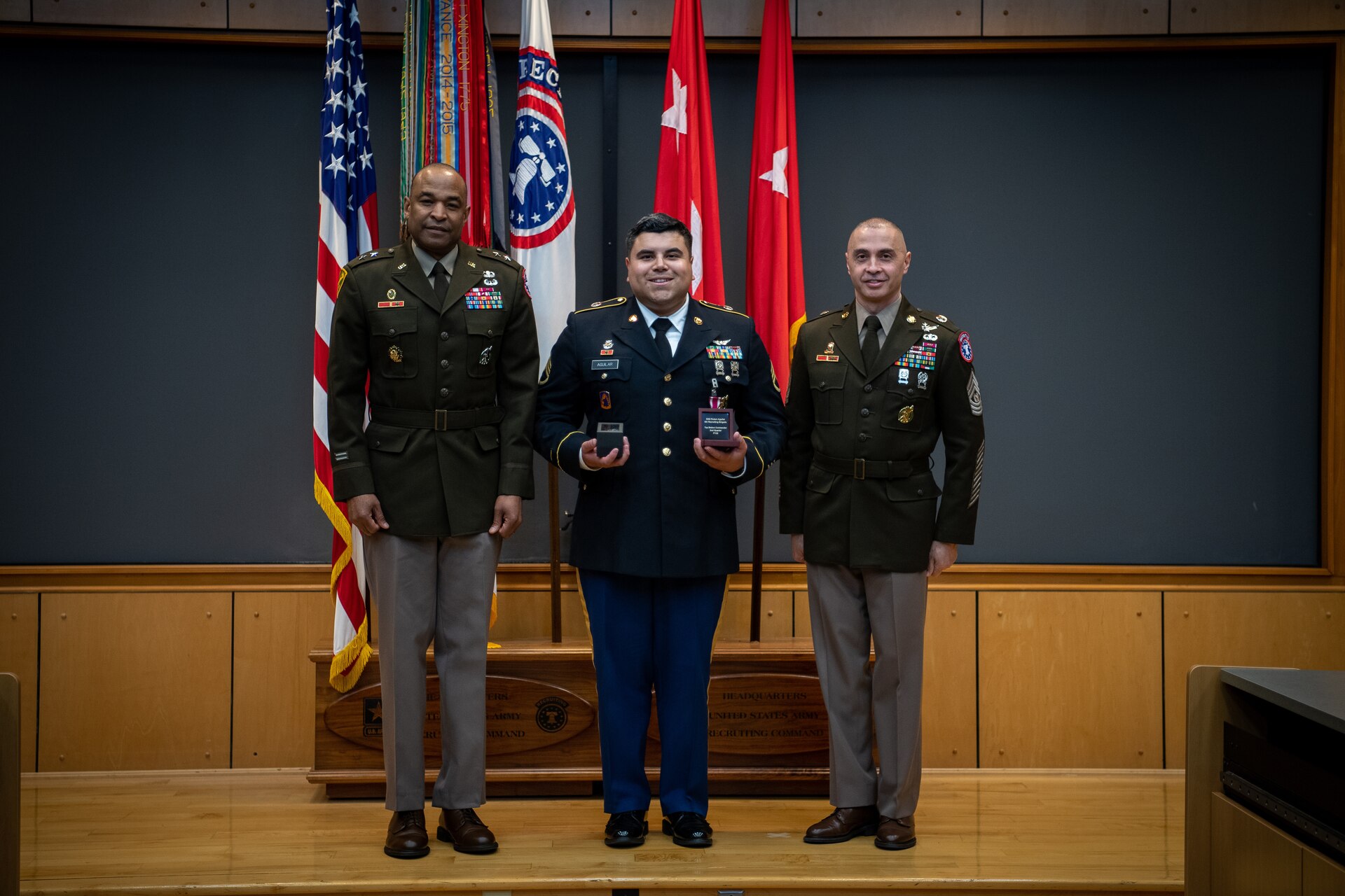army soldiers in uniform on a stage presenting awards.