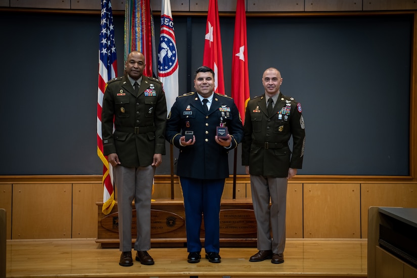 army soldiers in uniform on a stage presenting awards.