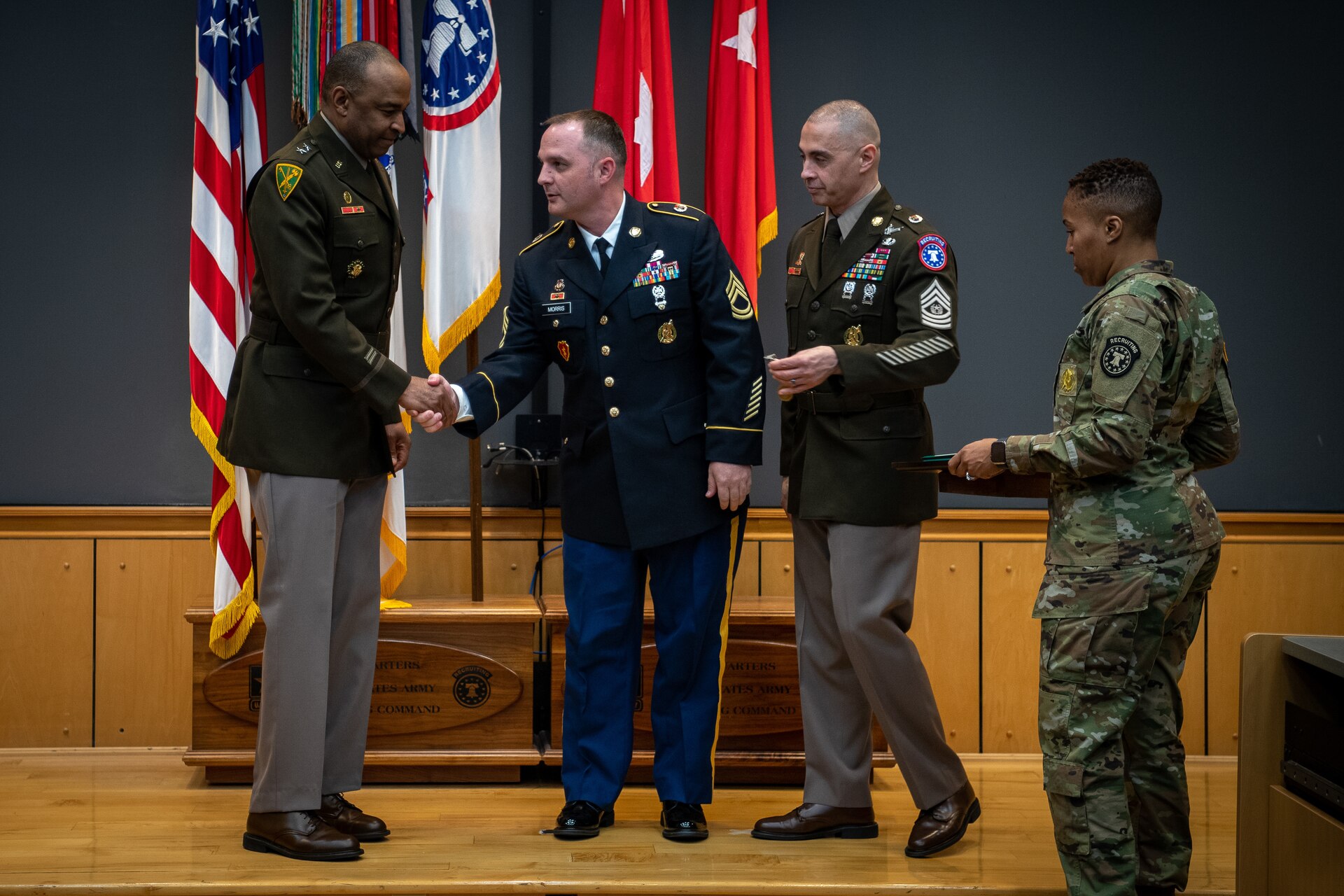 army soldiers in uniform on a stage presenting awards.