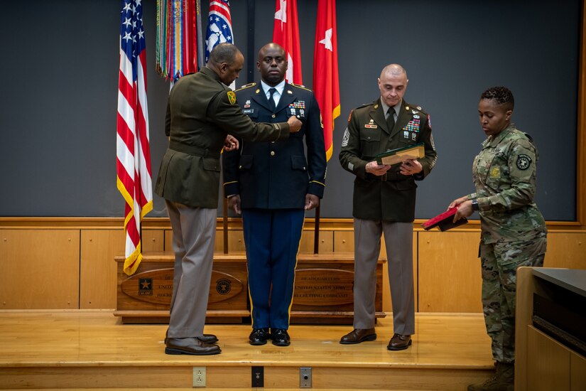 army soldiers in uniform on a stage presenting awards.