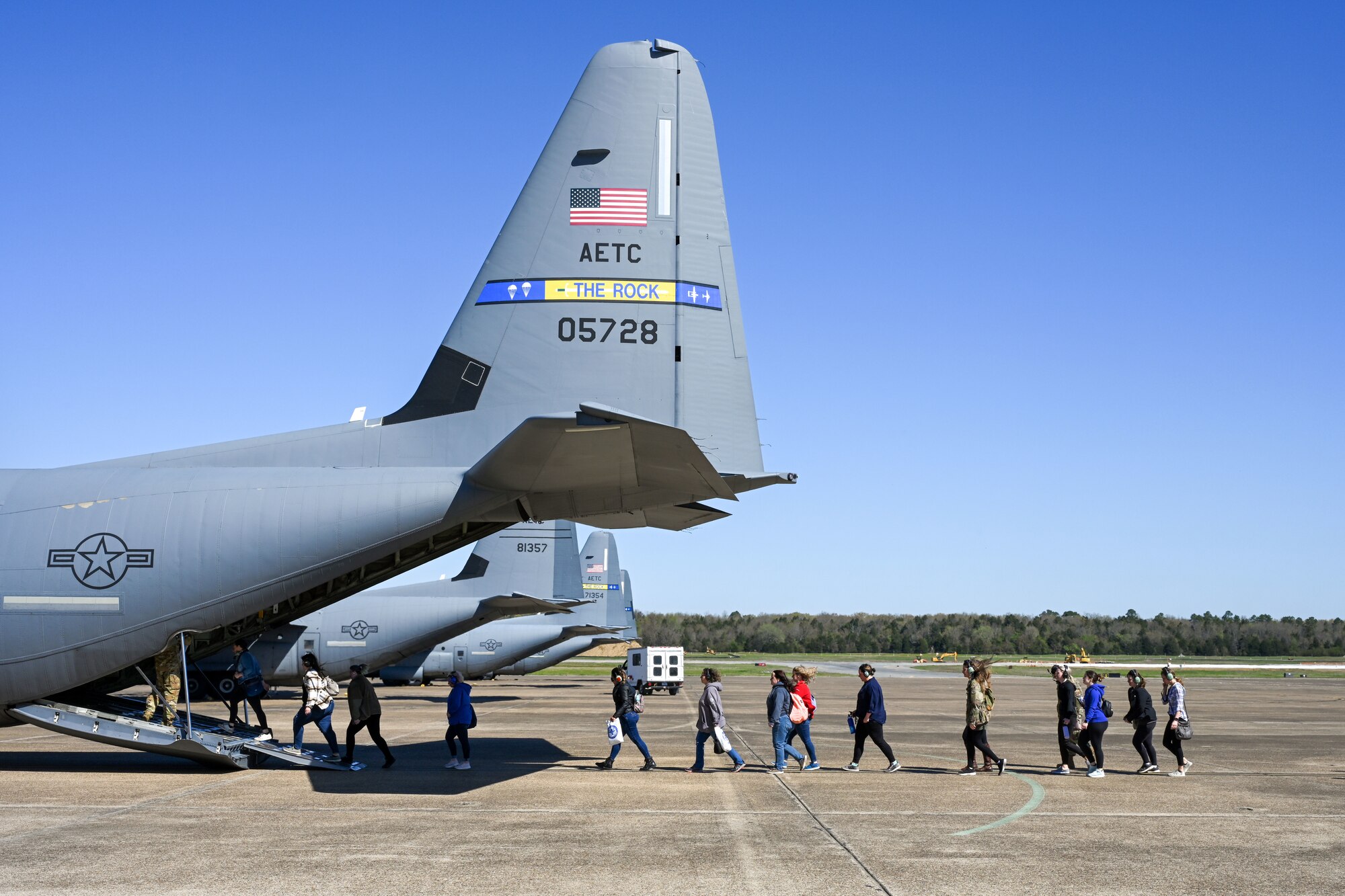 Military spouses board a C-130J Super Hercules during a spouse orientation flight