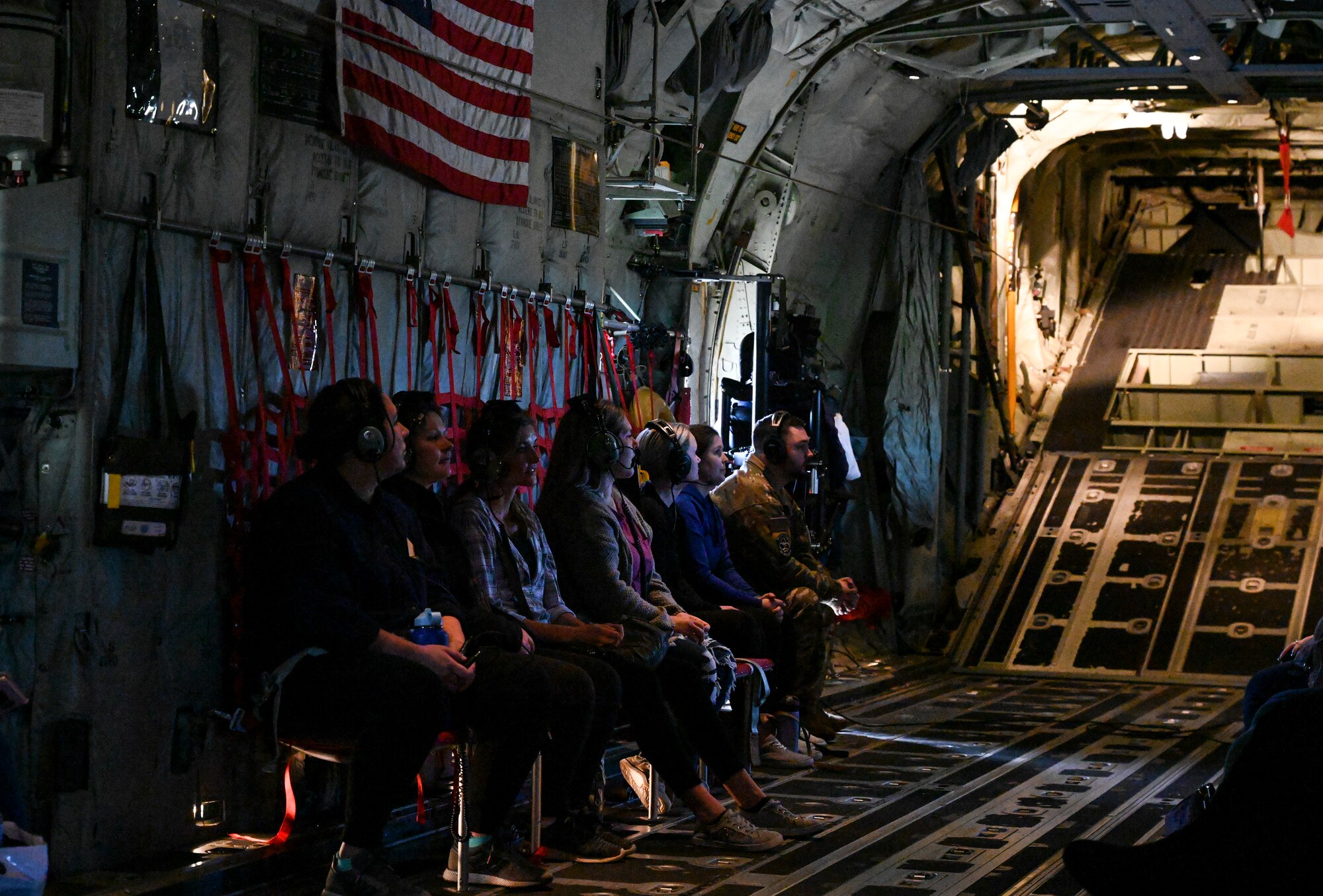 Military spouses sit in the back of a C-130J Super Hercules during an orientation flight
