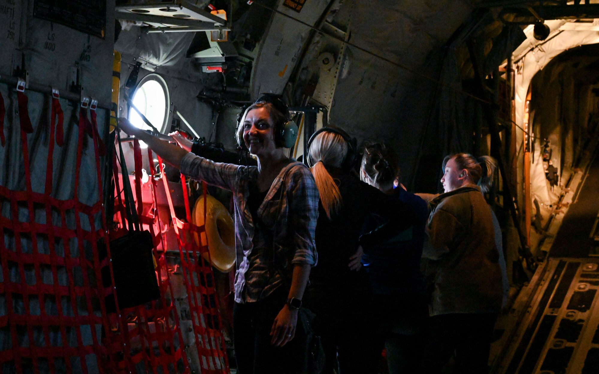 Military spouses look out the windows of a C-130J Super Hercules during an orientation flight