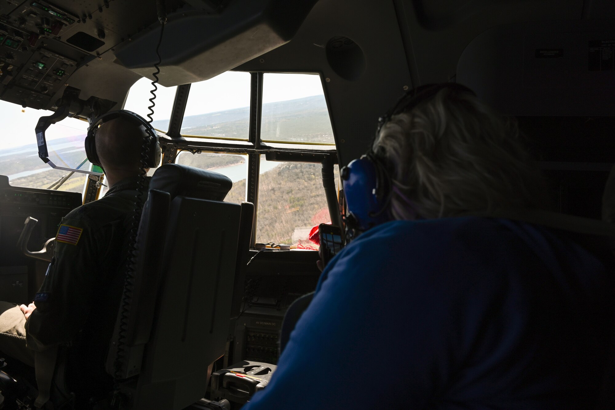 A service member’s spouse looks out the window on the flight deck of a C-130J Super Hercules during an orientation flight