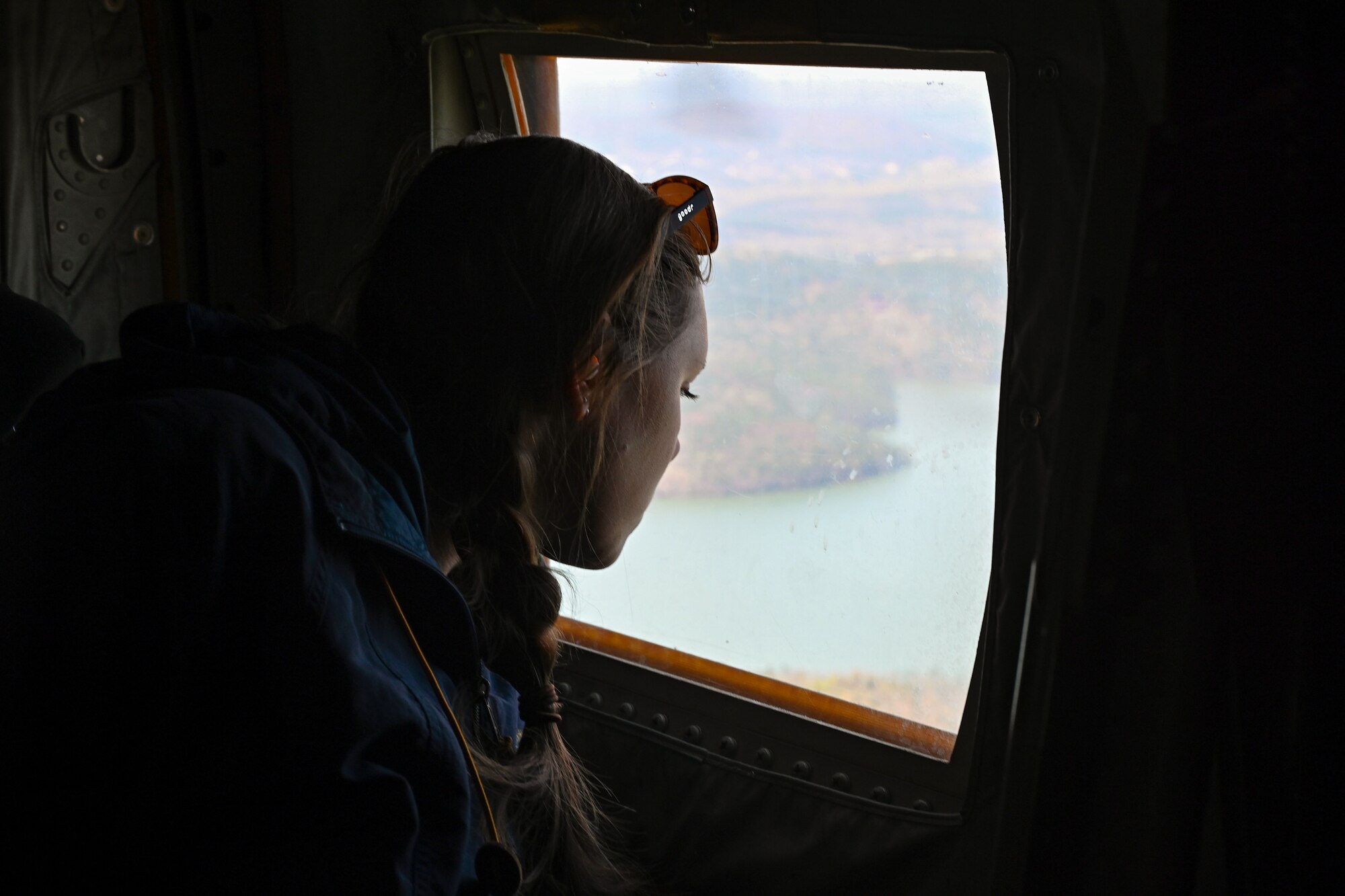A service member’s spouse looks out the window of a C-130J Super Hercules during an orientation flight