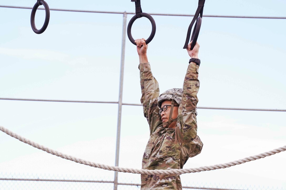 A soldier moves through monkey bars.