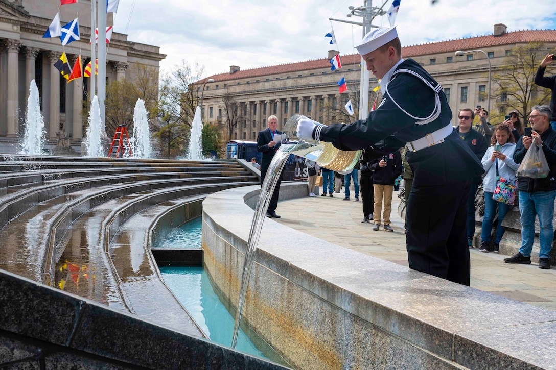 A sailor pours water into a fountain.