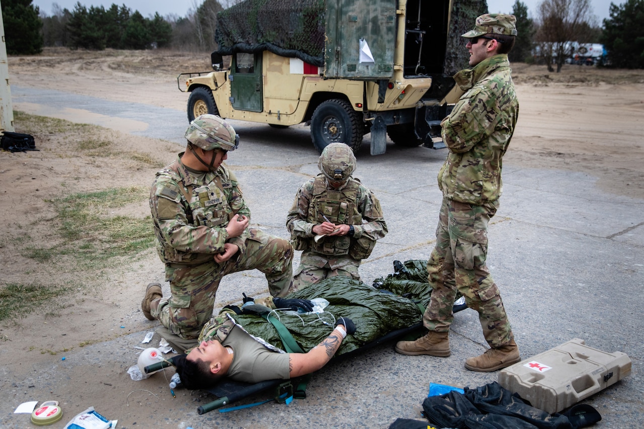 Three medics tend to a patient on a stretcher.