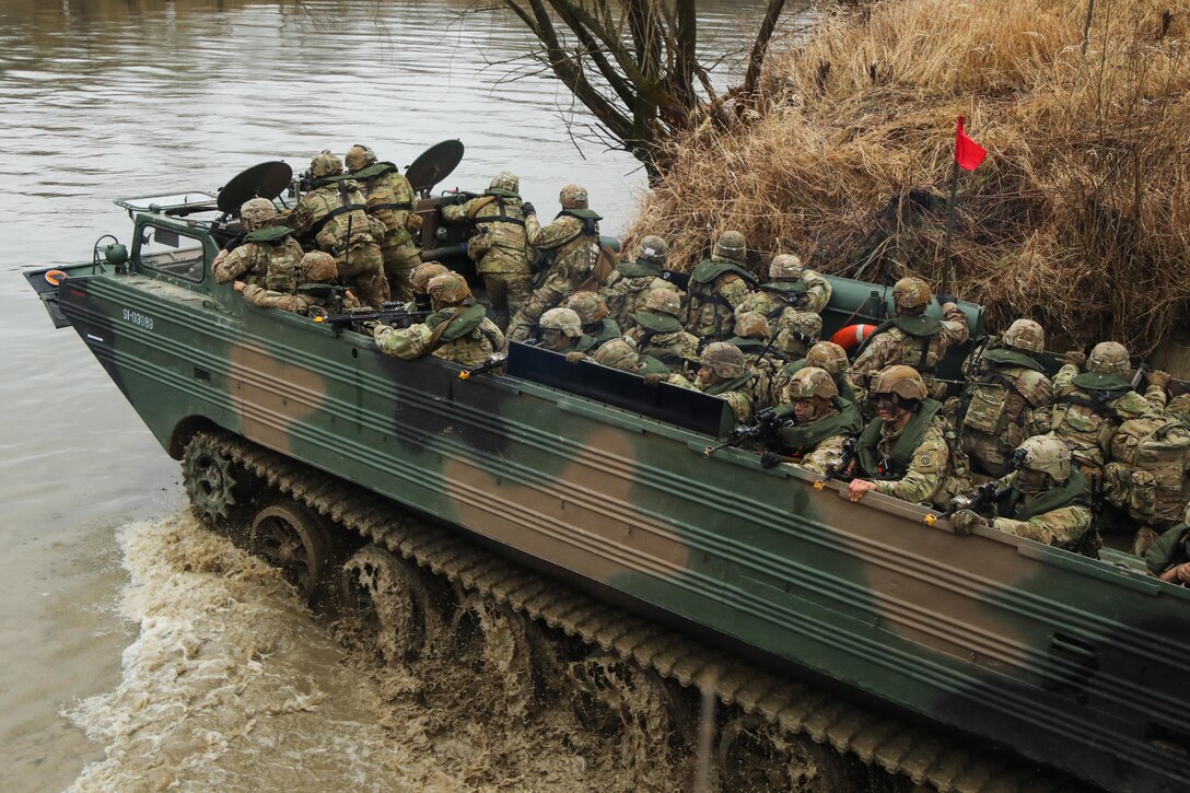 Troops in a vehicle cross a river.