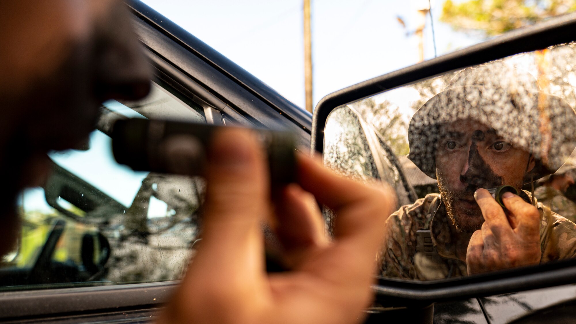 Photo of Airman applying camo paint to his face