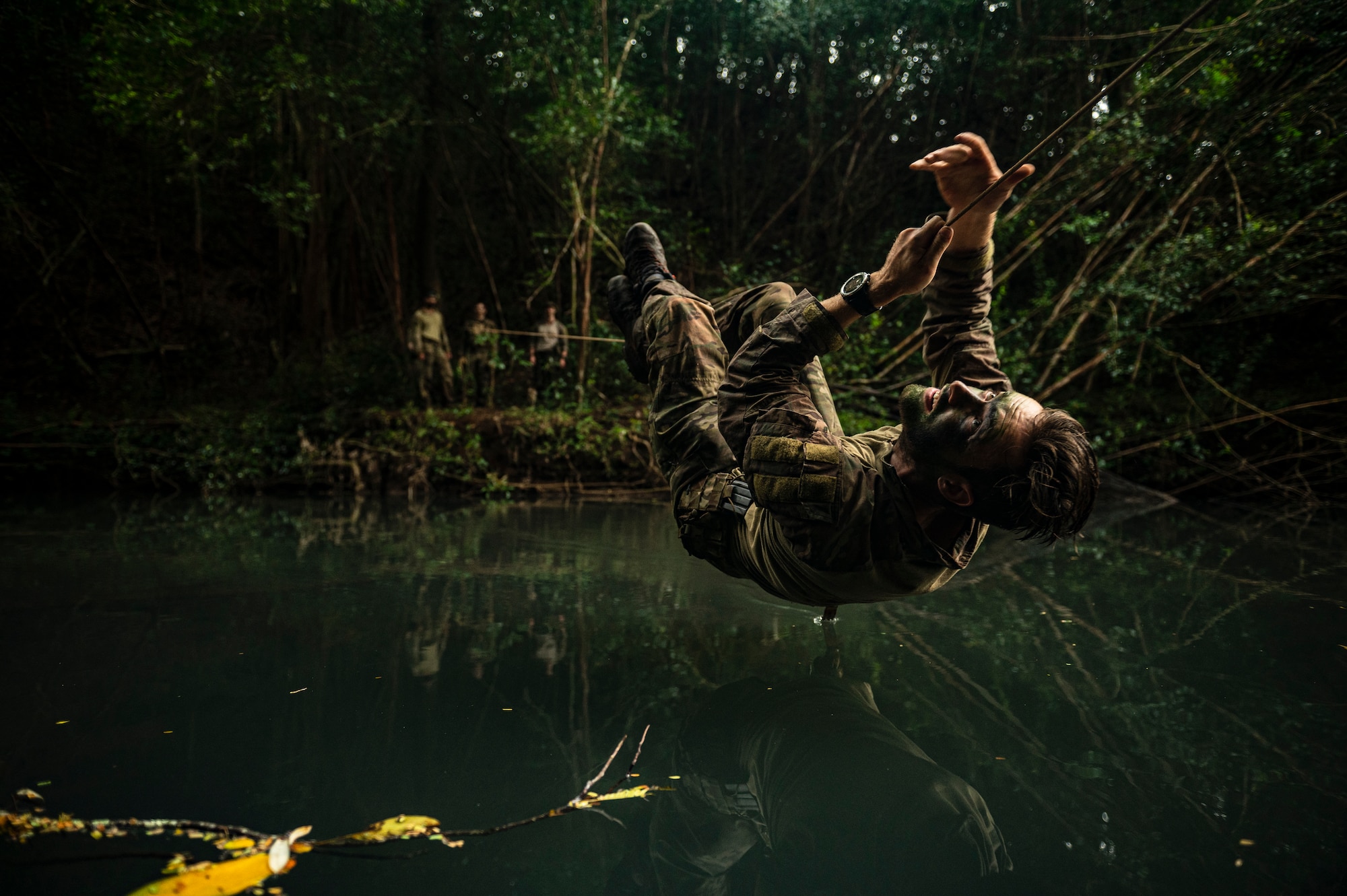 Photo of a Airman crossing a river on a rope