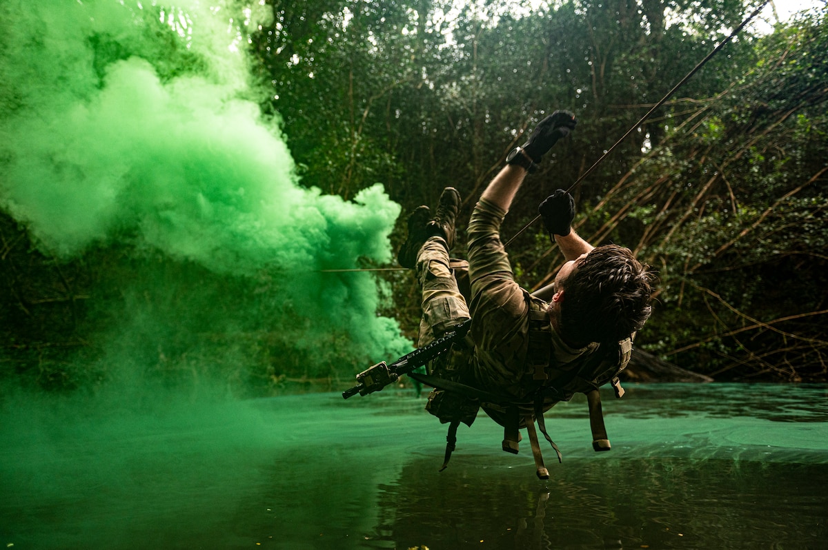 Photo of a Airman crossing a river on a rope