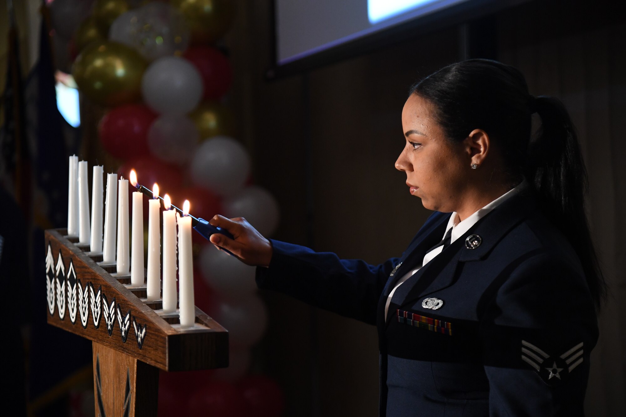 U.S. Air Force Senior Airman Shanna Riddick, 81st Security Forces Squadron visitor control center clerk, participates in a candle lighting ceremony during the Chief Master Sergeant Recognition Ceremony inside the Bay Breeze Event Center at Keesler Air Force Base, Mississippi, April 8, 2022. Four Keesler Airmen earned their chief master sergeant stripe during the 2022 promotion release. Chief master sergeants make up one percent of the Air Force enlisted force. (U.S. Air Force photo by Kemberly Groue)