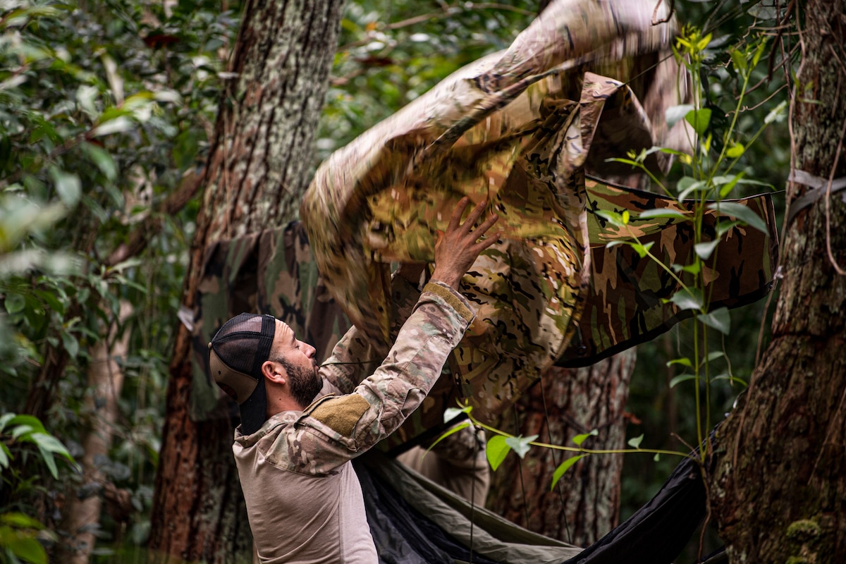 Photo of Airman throwing a poncho over a rope