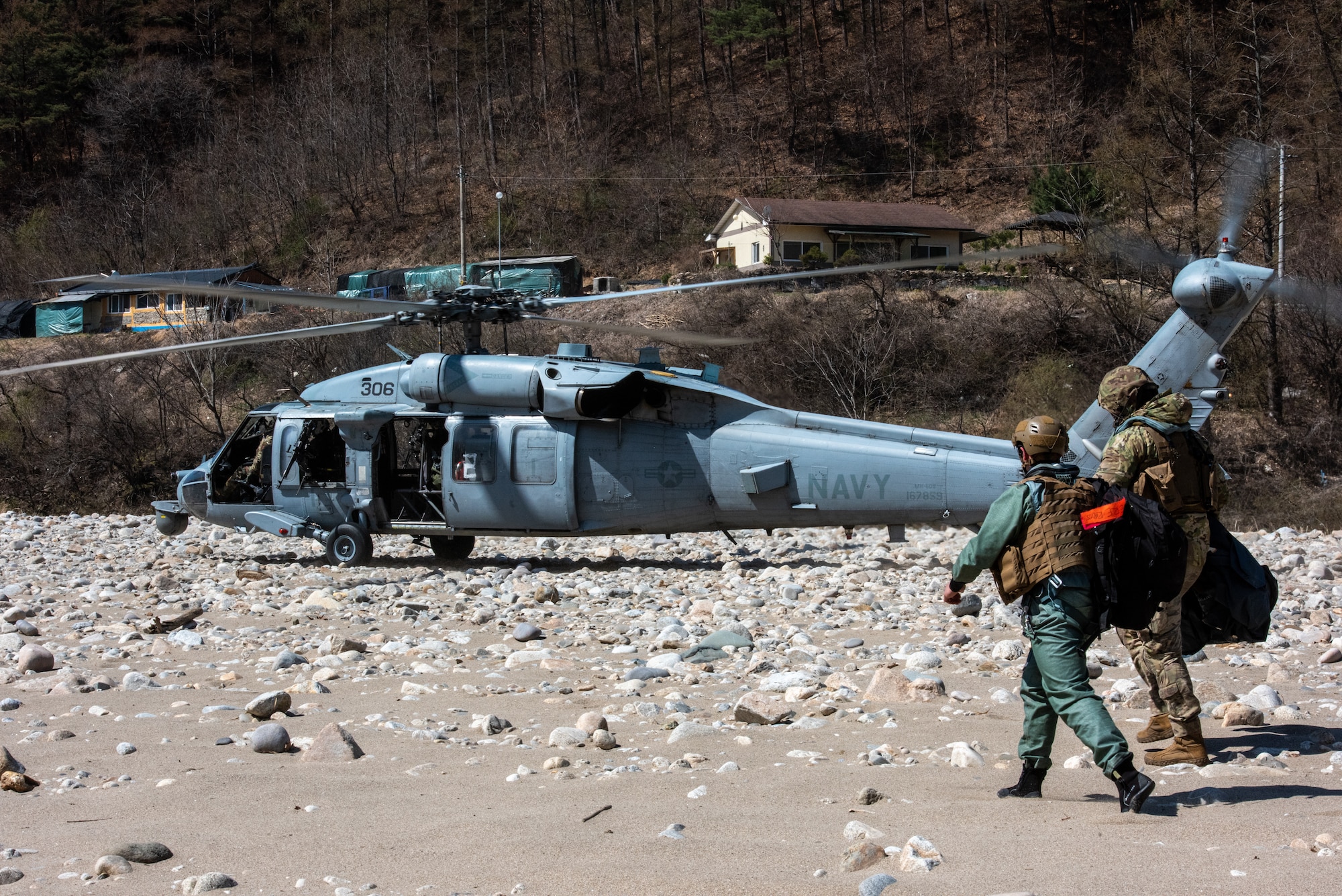 Staff Sgt. Ahron Rasabi, 51st Operations Support Squadron survival, evasion, resistance and escape specialist, and Naval Aircrewman (Helicopter) 1st Class Ryan Kuiper, Helicopter Sea Combat Squadron 85 crew chief, step to a MH-60S Seahawk during a combat search and rescue training event April 8, 2022.