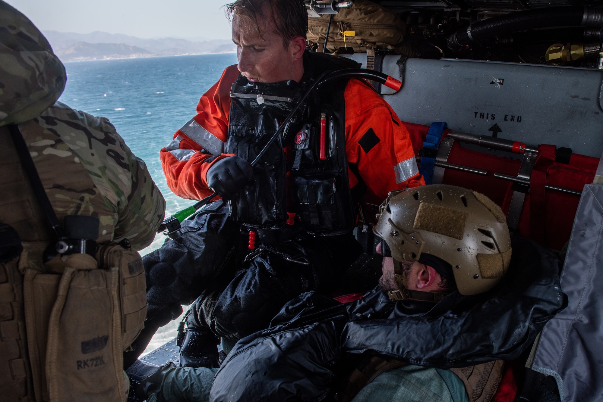 Naval Aircrewman (Helicopter) 1st Class Joshua Armitage, Helicopter Sea Combat Squadron 85 rescue swimmer, and Staff Sgt. Ahron Rasabi, 51st Operations Support Squadron survival, evasion, resistance and escape specialist, sit onboard a MH-60S Seahawk after practicing an open-sea rescue during a combat search and rescue training event April 8, 2022 over the Pacific Ocean.