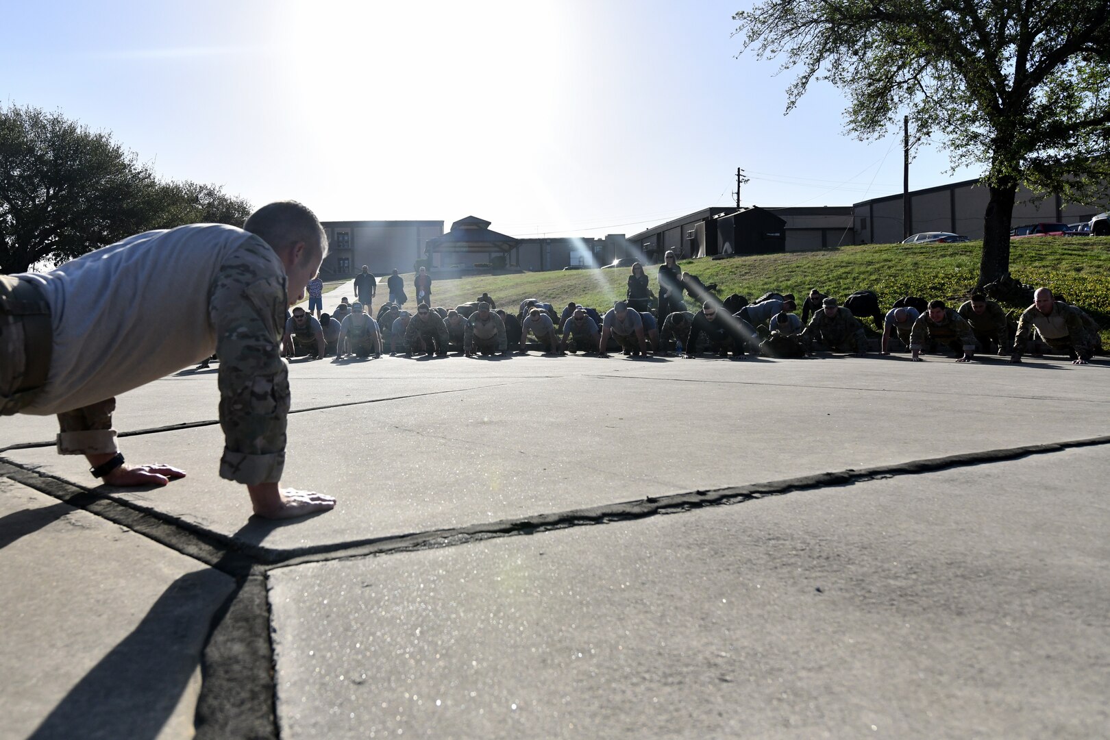 U.S. Air Force Chief Master Sgt. Todd Popovic, Special Warfare Training Wing command chief, leads participants in Memorial pushups during a rededication ceremony in honor of U.S. Air Force Lt. Col. William Schroeder and U.S. Air Force Staff Sgt. Scott Sather at the SWTW training compound Joint Base San Antonio, Chapman Training Annex, Apr. 8, 2022.  The wing and echelon units hosted a two and one-half mile ruck march followed by Memorial pushups and the unveiling of refitted memorials in coordination with Gold Star families (U.S. Air Force photo by Brian Boisvert)