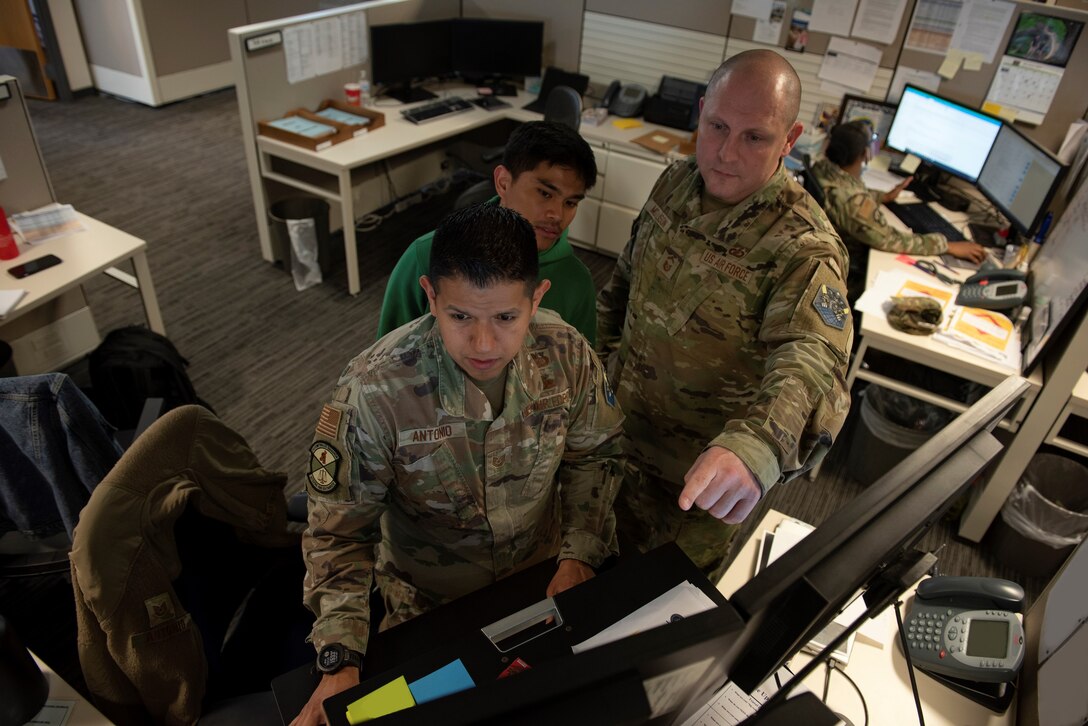 PETERSON SPACE FORCE BASE, Colo. – U.S. Air Force Senior Master Sgt. Johnathan Mollison, 21st comptroller squadron, Senior Enlisted Leader, right, and U.S. Air Force Tech. Sgt. Juan Antonio, 21st CPTS, non-commissioned officer in charge of financial operations, left, shows Airman 1st Class Eughine Garing, 21st CPTS, financial operations technician, middle, how to update pay records at Peterson Space Force Base, Colorado, Mar.18, 2022. Mollison ensures the proper training and development of 21st CPTS troops, enabling the support of the Peterson-Schriever Garrison mission. (This photo has been altered for security purposes by covering financial information on papers.) (U.S. Space Force photo by Master Sgt. Tabitha Lee.)