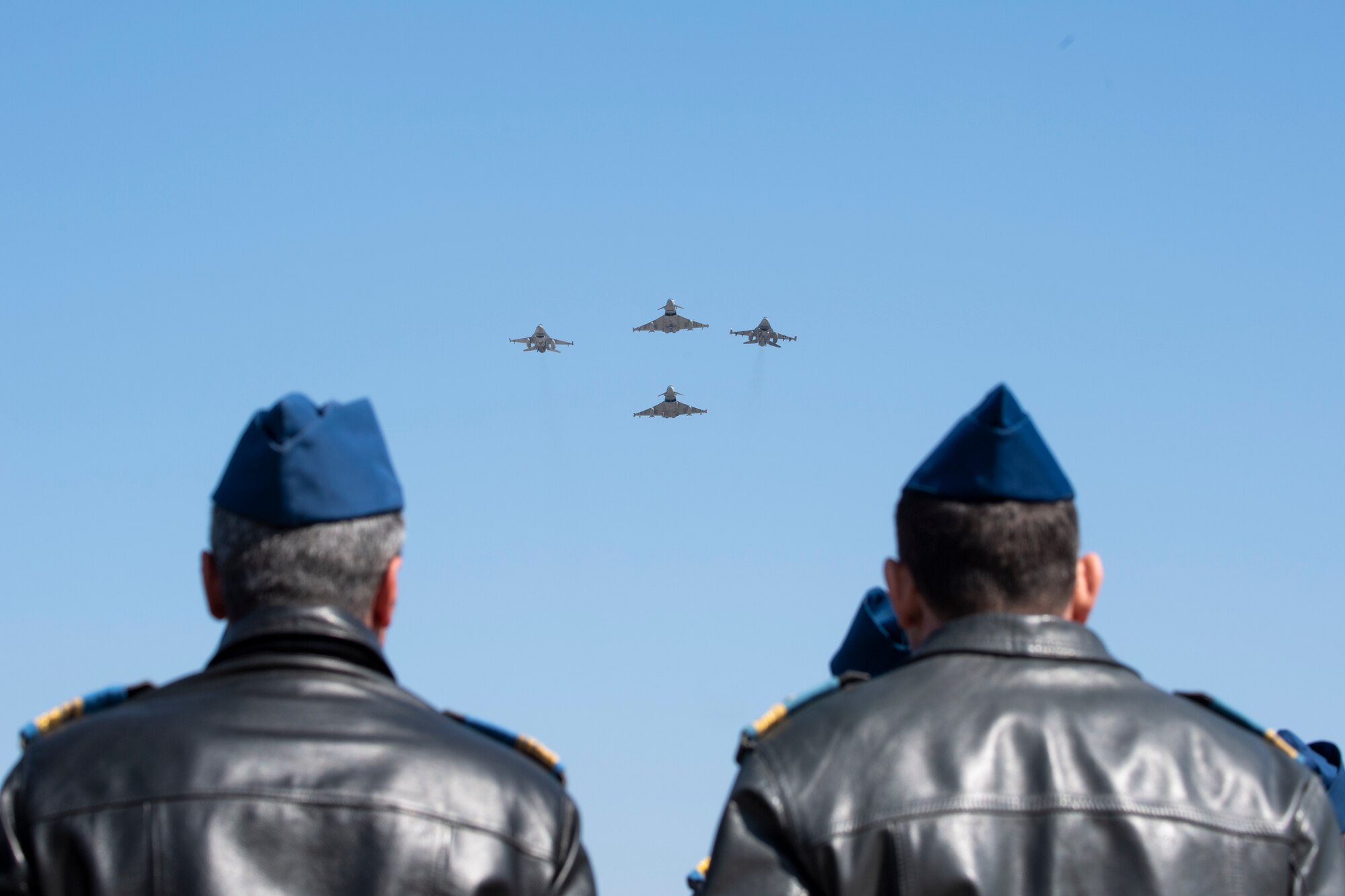 Photo of service members watching a fighter jet formation flyover