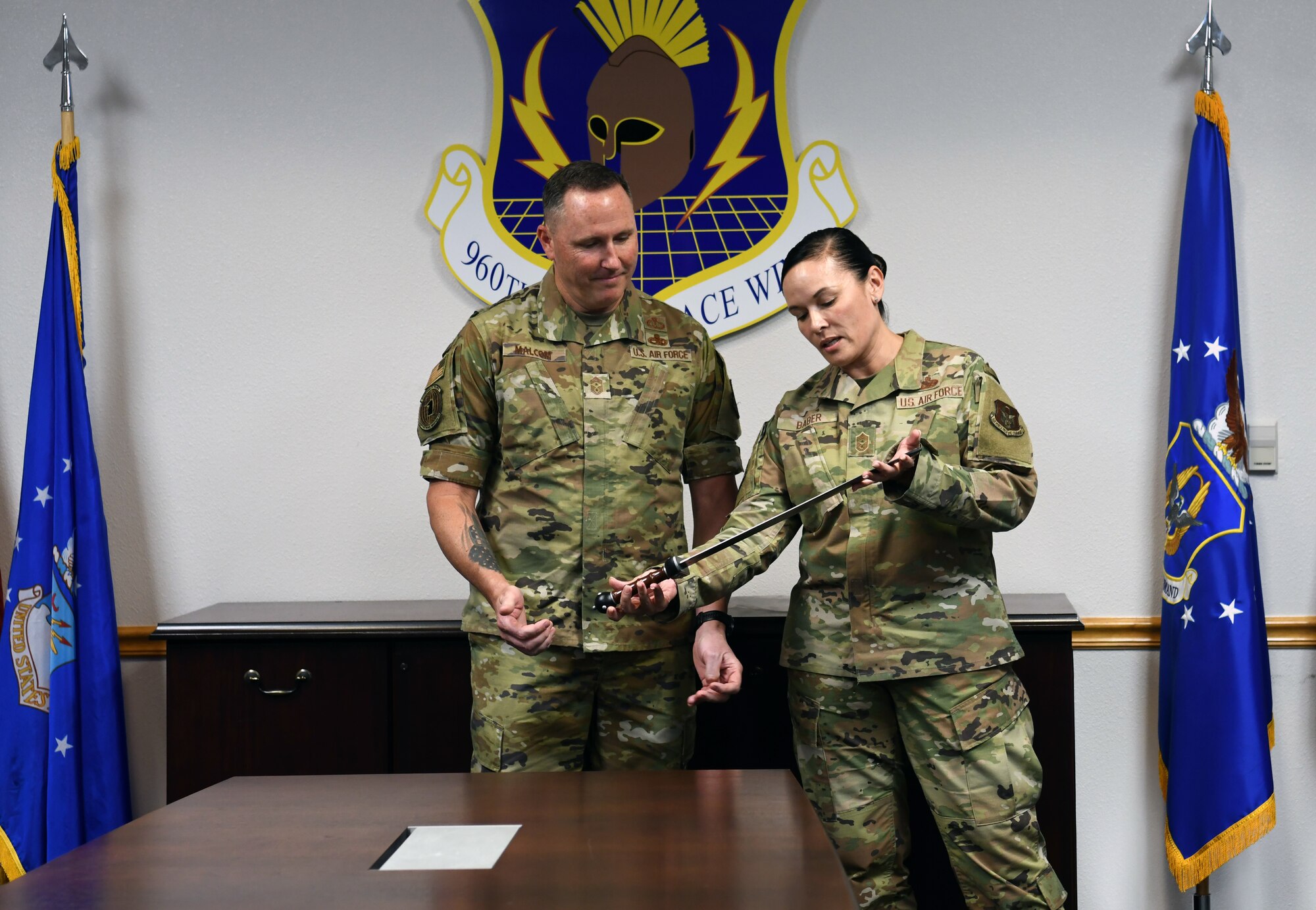 Chief Master Sgt. Billie M. Baber, 960th Cyberspace Wing command chief (left), presents a gladiator rudis to Chief Master Sgt. Jeremy N. Malcolm, 10th Air Force command chief, April 2, 2022, at Joint Base San Antonio-Chapman Training Annex, Texas. The rudis was a retirement gift to Malcolm. (U.S. Air Force photo by Kristian Carter)