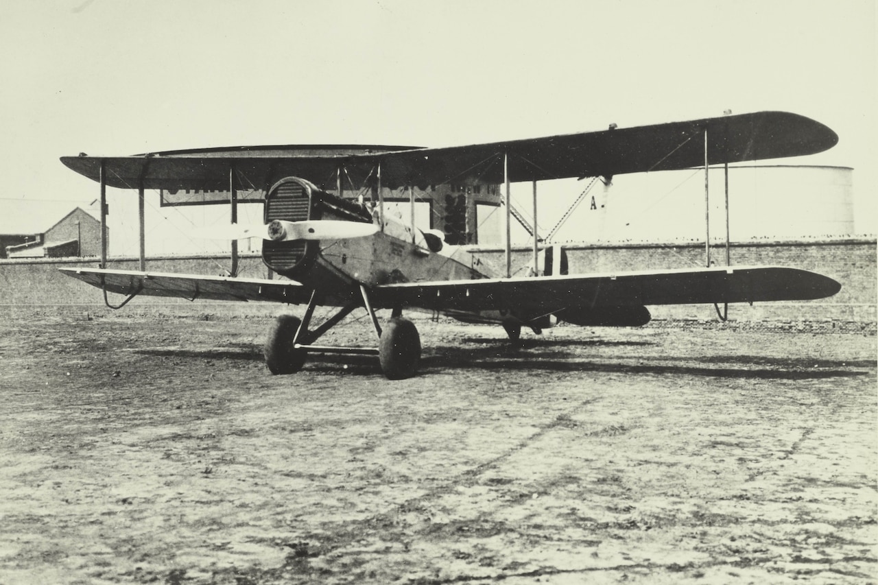 An early 20th century propeller airplane with two wings sits on the ground.