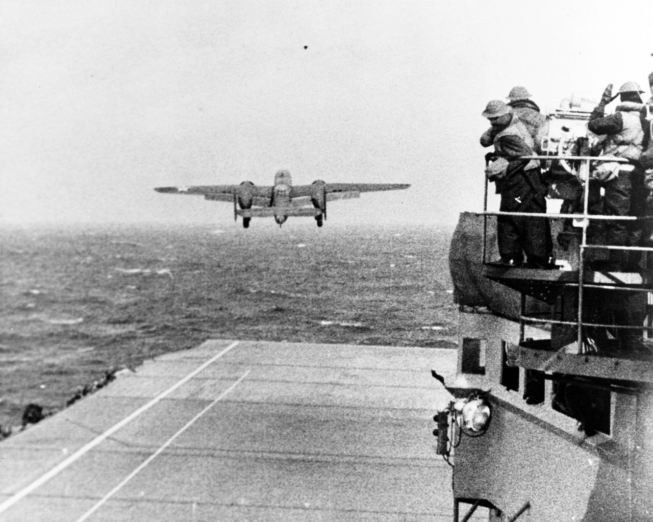 An aircraft takes off over the ocean from an aircraft carrier.