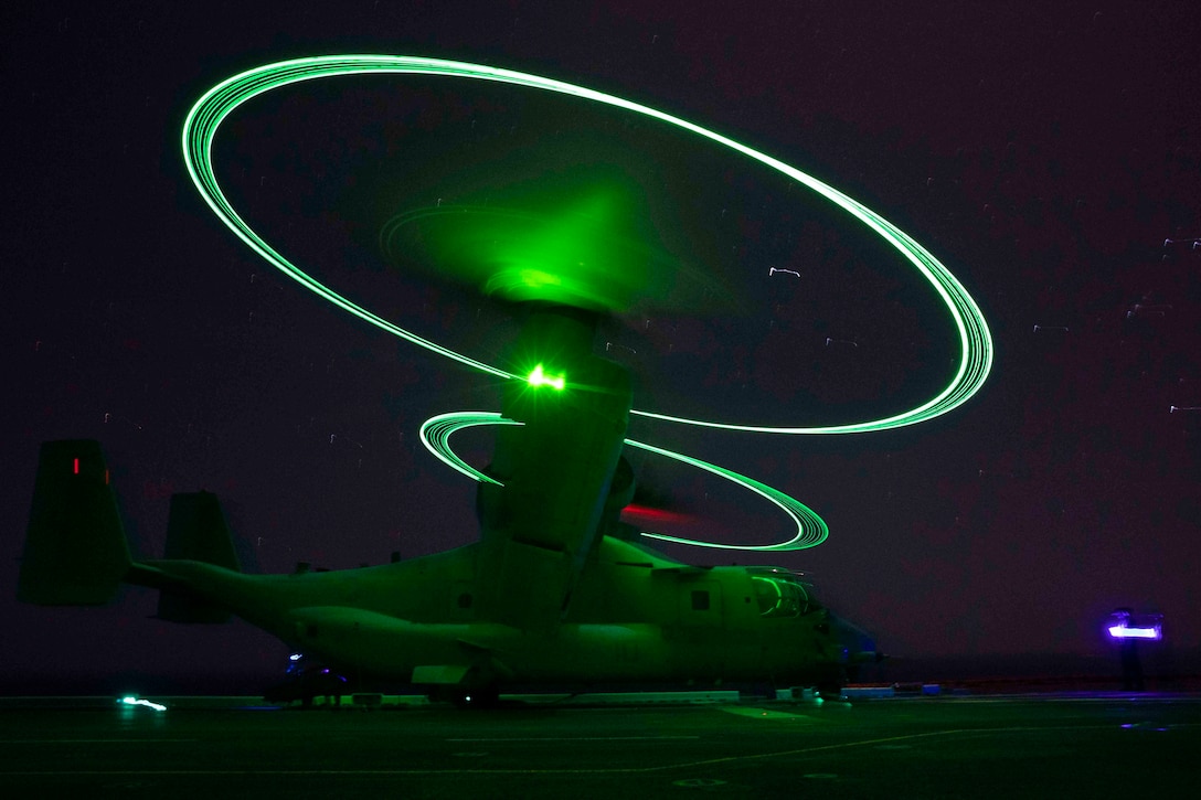 An aircraft idles on the deck of a ship at night.