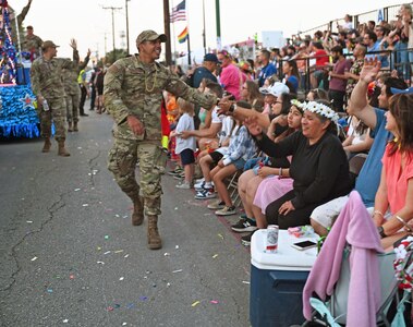 Senior Airman Eduardo Perez, 433rd Aircraft Maintenance Squadron hydraulics specialist, interacts with the crowd while walking in the San Antonio Fiesta Flambeau Parade April 9, 2022. The parade's theme this year was "Celebrating Literary Classics." (U.S. Air Force photo by Staff Sgt. Monet Villacorte)