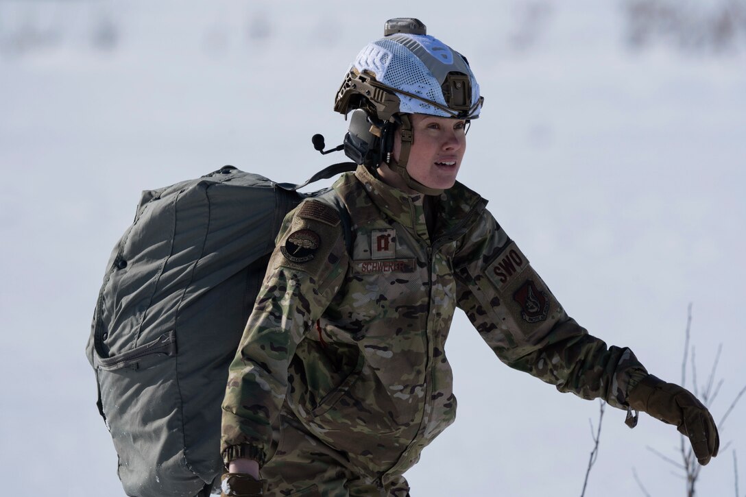 An airman carrying a backpack walks in the snow.