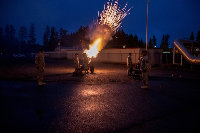 A large gun fires at night.