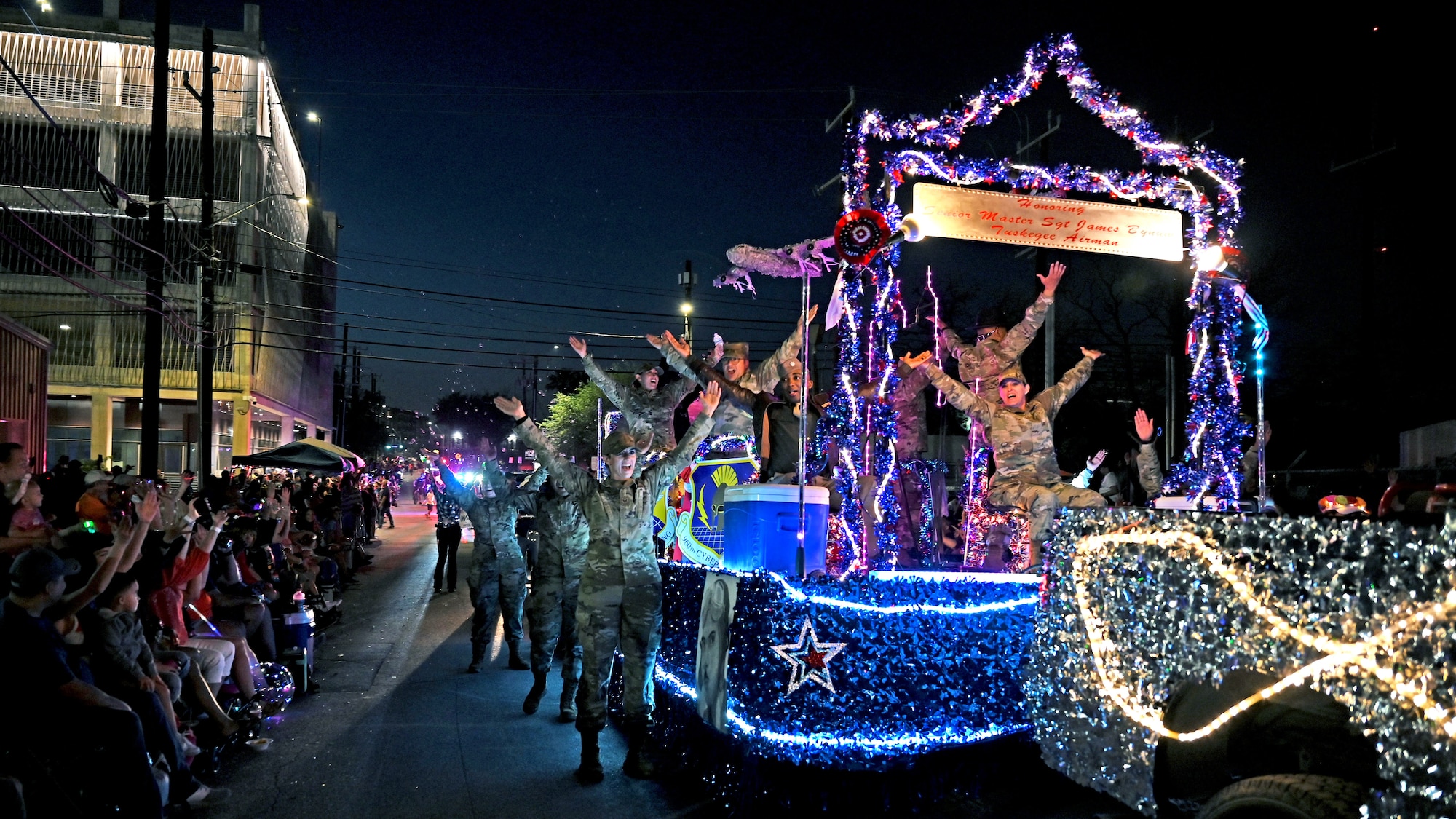 Reserve Citizen Airmen in the 433rd Airlift Wing, 960th Cyberspace Wing, 340th Flying Training Group and 23rd Intelligence Squadron sing along with the crowd during the Flambeau parade in downtown San Antonio, April 9, 2022. This was the first time the four South Texas Reserve units worked together on a float for the annual Fiesta celebration. (U.S. Air Force photo by Master Sgt. Samantha Mathison)