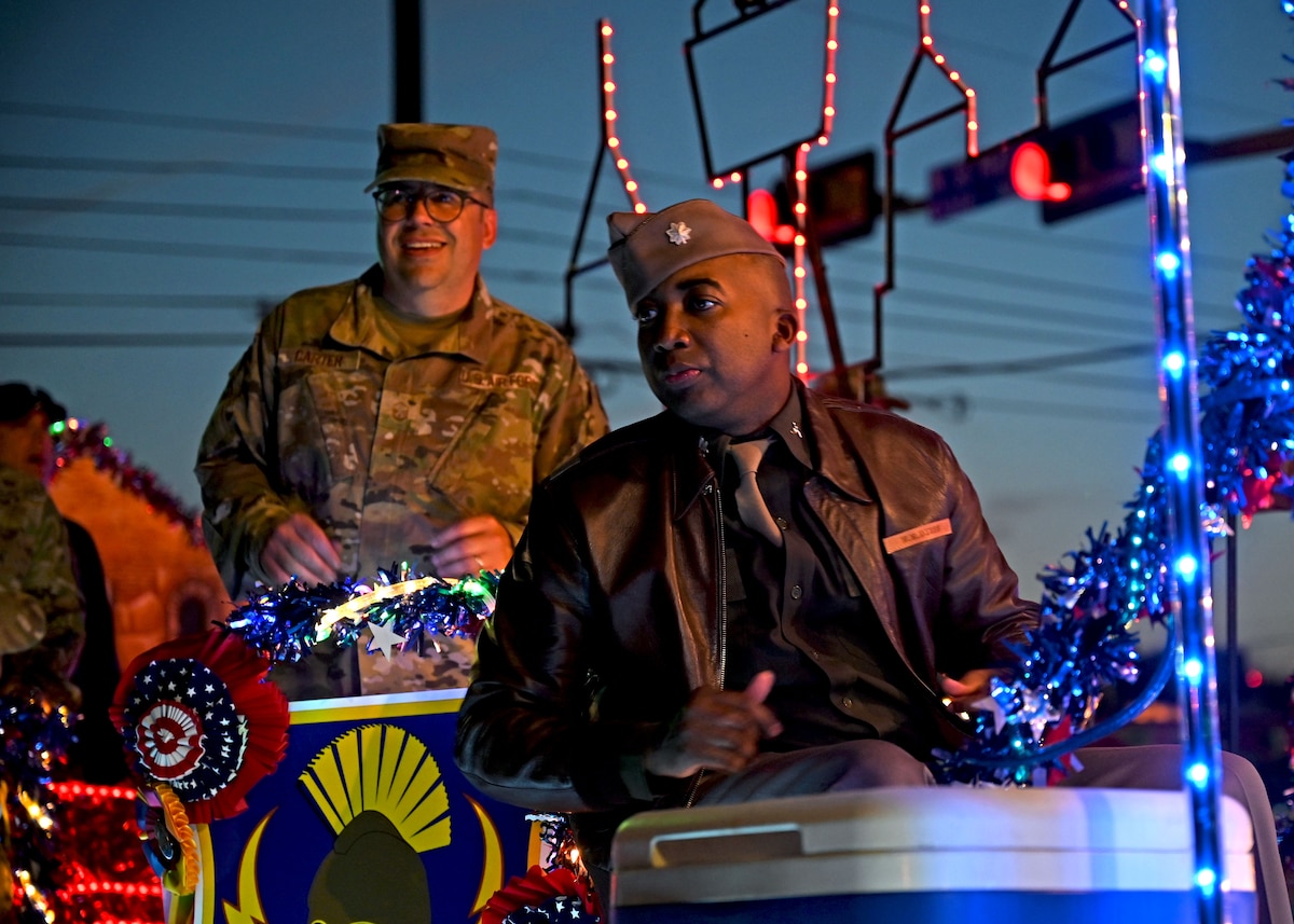 Lt. Col. Timothy Wade, 433rd Airlift Wing chief of public affairs, and Master Sgt. Kristian Carter, 433rd AW public affairs superintendent, look towards the crowd while riding on a float for the Fiesta Flambeau parade in downtown San Antonio, April 9, 2022. The Flambeau parade is one of three parades hosted during the annual Fiesta celebration. (U.S. Air Force photo by Master Sgt. Samantha Mathison)