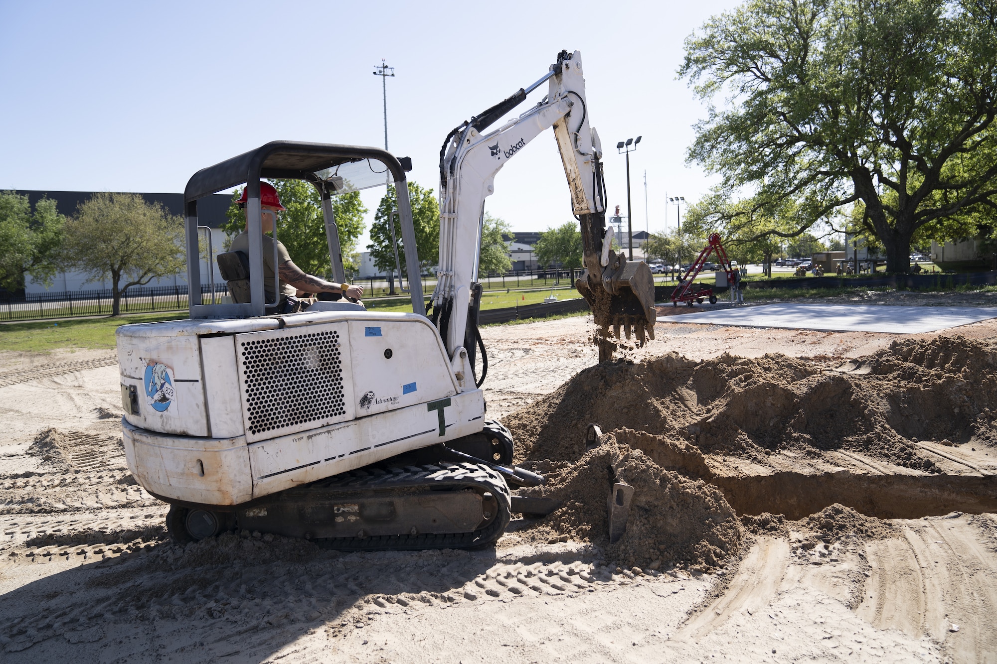 An 823rd Rapid Engineer Deployable Heavy Operational Repair Squadron Engineer Airman operates an excavator at Keesler Air Force Base, Mississippi, April 13, 2022. The squadron is working to expand the Air Expeditionary Force compound to allow radio frequency transmissions and cyber transport courses increase efficiency in training. (U.S. Air Force photo by Airman 1st Class Trenten Walters)