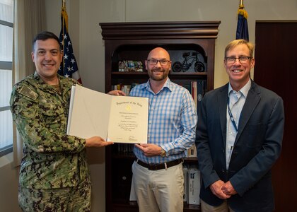 (left) Capt. David Back, Naval Surface Warfare Center commanding officer and (right) Dr. Peter Adair, NSWC PCD technical director present Stephen (Rusty) Weathers, NSWC PCD Airborne Mine Neutralization System lead systems engineer with the Department of the Navy’s Meritorious Civilian Service Award on March 28. As a result of Weathers' system-of-system approach, the program realized a $66M cost avoidance due to his analysis and bringing forth his recommendation to change the maintenance philosophy of the Launch and Handling System from a required 5-year overhaul to a performance based overhaul. (U.S. Navy photo by Anthony Powers)