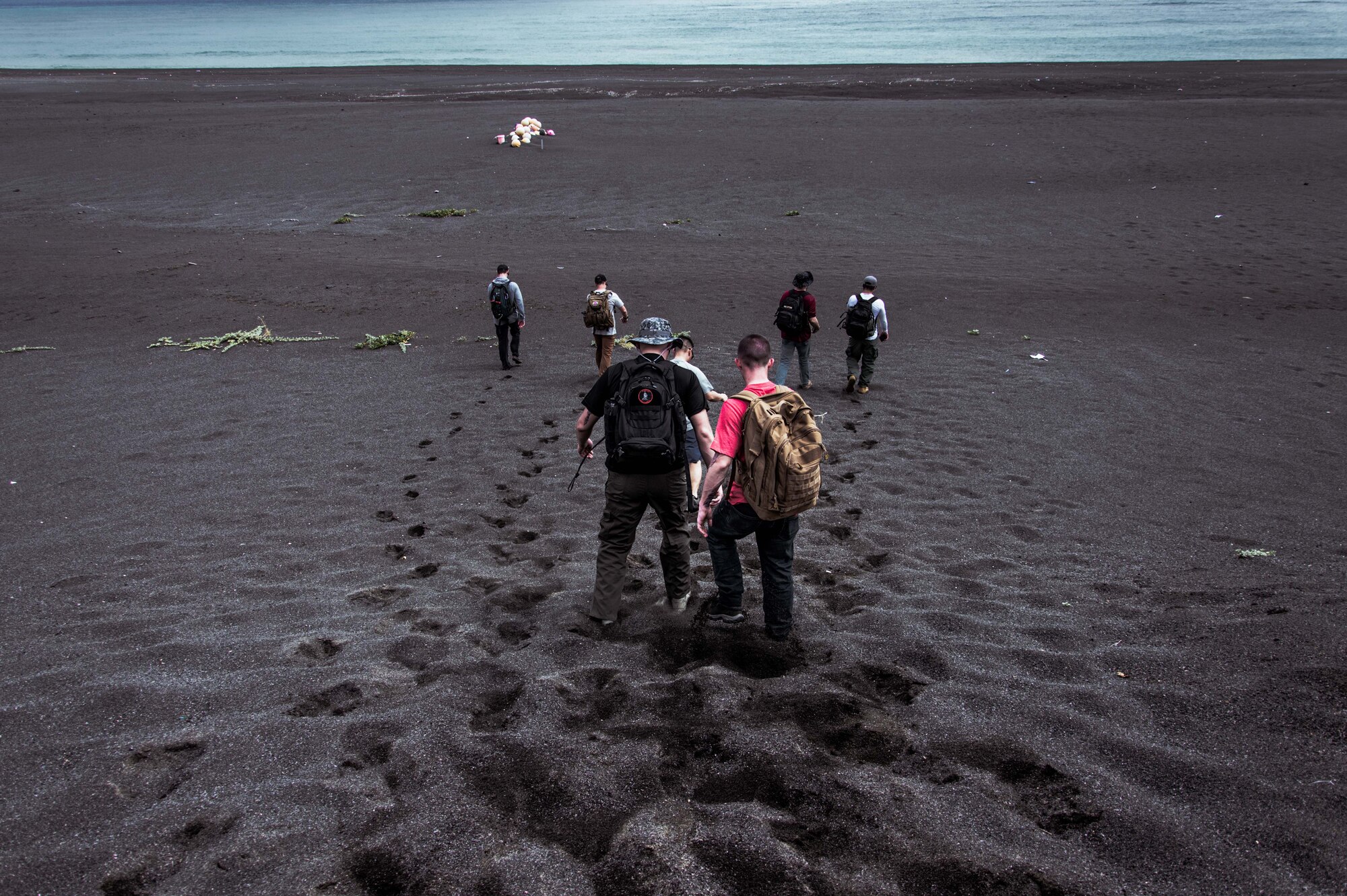 Airmen hike down to a beach.